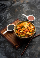 Egg Schezwan/hakka noodles, popular indochinese food served in a bowl with chopsticks. selective focus
