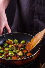 young woman fries Brussels sprouts on a frying pan