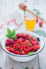 Fresh organic Red berries in a white enamel bowl