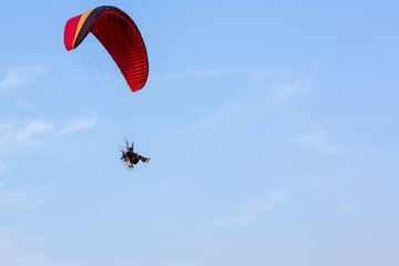 Adventure man active extreme sport pilot flying in sky with paramotor engine glider parachute. Paramotor flying on the sky at sunset. 