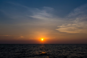 Naklejka na ściany i meble Bright sunset with large yellow sun under the sea surface. sunrise in the sea. Beautiful sunset above the sea. Tropical sunset on the beach.