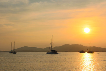 Sunset and dawn at sea against a backdrop of mountains and boats