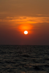 Bright sunset with large yellow sun under the sea surface. sunrise in the sea. Beautiful sunset above the sea. Tropical sunset on the beach.