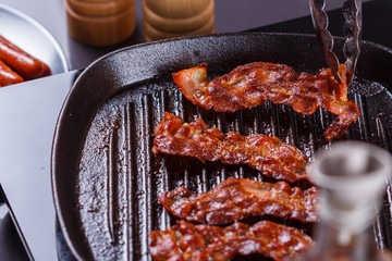 young woman in a gray apron fries bacon