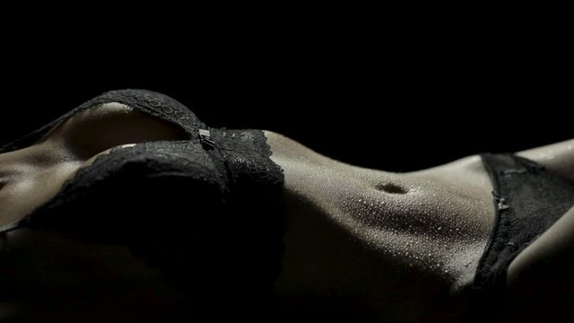 Close-up of a sexy woman's body lying down in black lace lingerie as her hips are writhing around