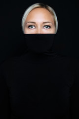 Studio portrait of beautiful elegant woman hiding face in black turtleneck