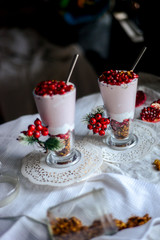 tasty breakfast  from creamy pomegranate dessert with homemade granola in hight glasses decorated with red berries on the ight background in the winter morning