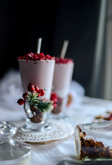 tasty breakfast  from creamy pomegranate dessert with homemade granola in hight glasses decorated with red berries on the ight background in the winter morning