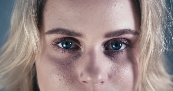 Closeup of eyes of a blond girl with beautiful blue eyes looking into camera and blinking.
