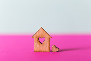 Obraz na płótnie Canvas Closeup wooden house with hole in form of heart on vibrant two-colored background.