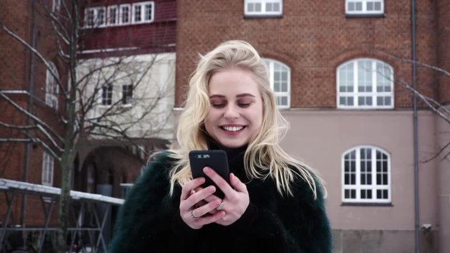 Young happy teen girl holding her mobile phone and celebrating because she just won a lottery prize.
