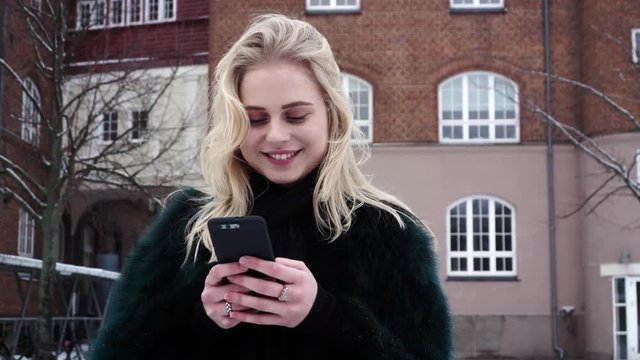 Cute shy blond teen girl is happy because she is texting and flirting via sms with her new sweet boyfriend.