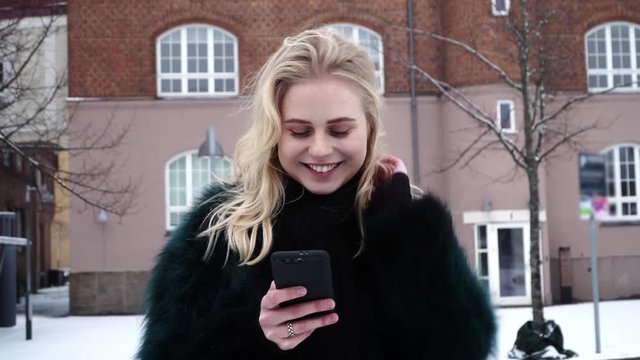 Pretty and happy teen girl just receive a sweet sms from her love and now she is standing being shy and smiling.