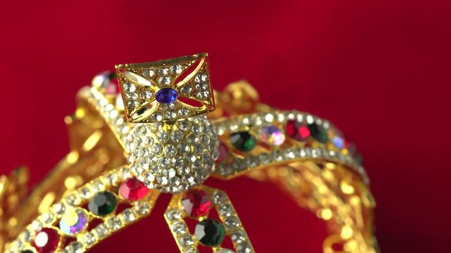 Gold diamond crown or decorative pageant accessory close up focus on the top. Slowly rotation on the red royal color surface. 4k, uhd.