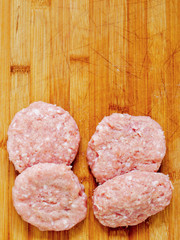 Fresh uncooked turkey burgers on a wooden board, Copy paste.