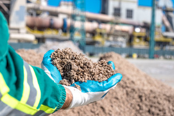 Man holding shredded paper in front of rotary cement kiln used as alternative fuel