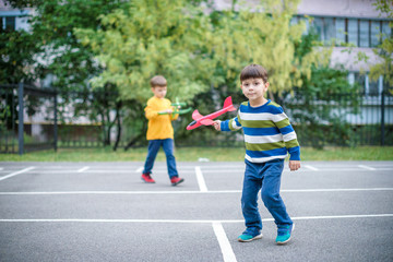 Happy two brother kids playing with toy airplane against blue summer sky background.