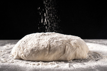 Fototapeta na wymiar dough with flour on a black background