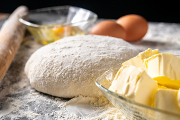White flour with eggs, butter and dough on a cooking board