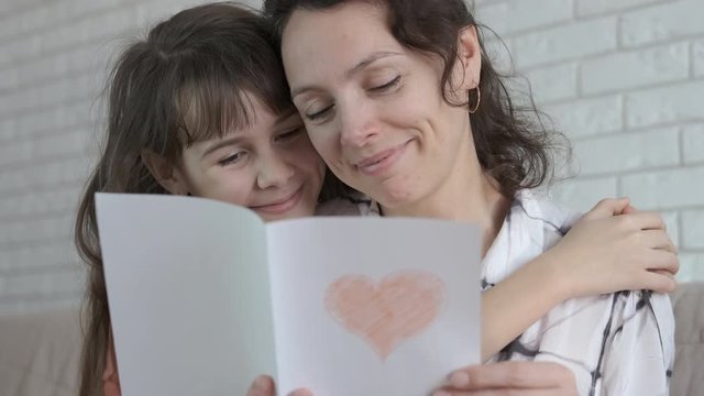 Mothers Day. Happy mother looks at a postcard presented by her daughter.