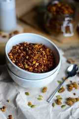 tasty homemade oats granola with nuts and berries in white ceramic bowl served with coconut milk on the wood table for breakfast early in the morning
