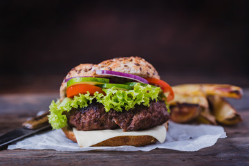 Home made hamburger with green salad on brown wooden background.