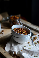 tasty homemade oats granola with nuts and berries in white ceramic bowl served with coconut milk on the wood table for breakfast early in the morning