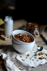 tasty homemade oats granola with nuts and berries in white ceramic bowl served with coconut milk on the wood table for breakfast early in the morning