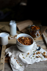 tasty homemade oats granola with nuts and berries in white ceramic bowl served with coconut milk on the wood table for breakfast early in the morning