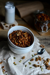 tasty homemade oats granola with nuts and berries in white ceramic bowl served with coconut milk on the wood table for breakfast early in the morning