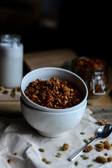 tasty homemade oats granola with nuts and berries in white ceramic bowl served with coconut milk on the wood table for breakfast early in the morning