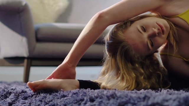 Young women on a mat in the home preforming the Parivrtta Janu Sirsasana (Revolved Head-to-Knee) yoga pose.