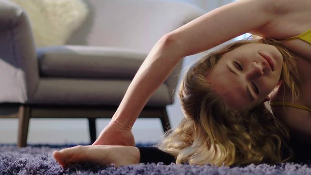 Young women on a mat in the home preforming the Parivrtta Janu Sirsasana (Revolved Head-to-Knee) yoga pose.