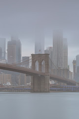 Fototapeta na wymiar Brooklyn bridge and world trade center from East river on a foggy day with long exposure