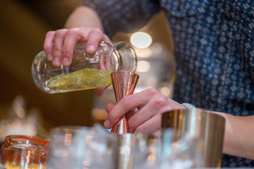 barman preparing cocktai and  pours liquid into the jigger in a cocktail bar