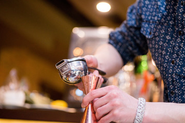 barman preparing cocktai and  pours liquid into the jigger in a cocktail bar