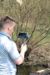 A young man videotaping on a smartphone. Uses gimbal to get smooth footage. Closely watching the movie shooting.
