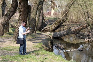 A young man videotaping on a smartphone. Uses gimbal to get smooth footage. Closely watching the movie shooting.