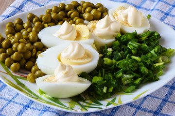 Boiled eggs under mayonnaise with green peas and green onions. A traditional russian dish.