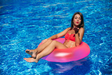Young pretty fashion woman body in swimming pool. Beautiful girl holding a rubber ring