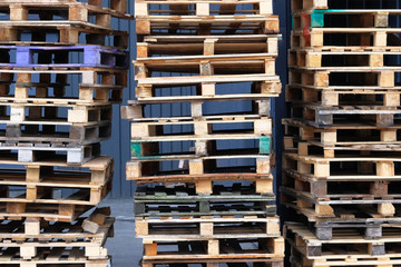 Pallets background. Stacks of colorful rough wooden pallets at warehouse in industrial yard. Cargo and shipping concept.