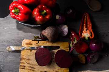 STILL LIFE OF RED PEPPERS WITH ONIONS ON A RUSTIC WOODEN TABLE