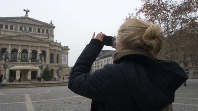Slow Motion: Woman with Blonde hair taking a picture with her mobile phone of the Alte Oper in Frankfurt