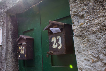 Genoa/Italy - October 18 2017: Two old metal black and beautiful mailboxes on a green door on the outskirts of the city Genoa in bright daylight. Genoa, Italy living area. Post, mail, old, post boxes.