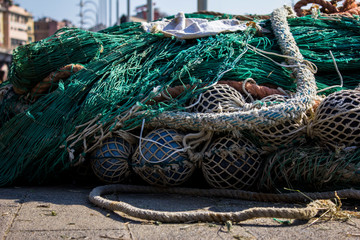 Ropes, hawsers,  buoys, fenders and green and grey sea mesh, net on the seaside in city port, harbour, marine of Genoa