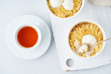 Apple crumble with ice cream, streusel. Morning breakfast with tea on a light gray table. Top view, close up