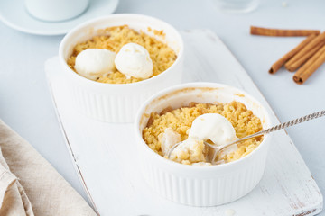 Apple crumble with ice cream, spoon with streusel. Morning breakfast on a light gray table. Side view, close up