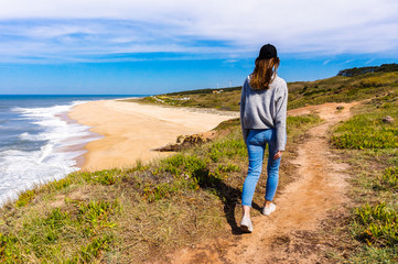 Young woman goes to deserted sandy beach in Nazare