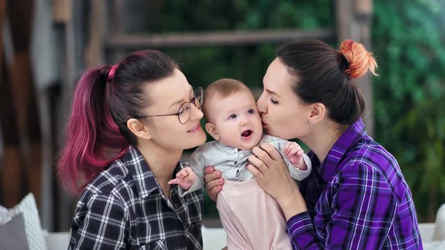 Two happy mother enjoying kissing and hugging little cute daughter medium shot