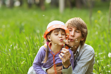 Fototapeta premium father and daughter blowing on dandelions in a summer